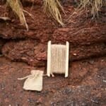 Miniatuur spinnende wolk met houten spool en zakje op rots in buitenomgeving.