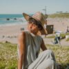 Cool Shoe Corp. strohoed HAT BROWN op een vrouw haar hoofd op het strand – unisex zomerse hoed van gevlochten stro, 58 cm universele pasvorm