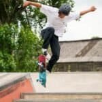 Skateboarder maakt een trick op een ramp in het skatepark, gekleed in casual kleding en een helm voor veiligheid.