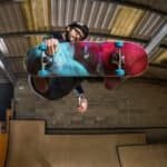 Kunstskater in de lucht tijdens een sprong in een binnen skatepark.