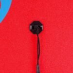 Rope attachment on a red surfboard or skateboard, close-up detail.
