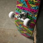 Plies plastic skateboard wheels and trucks on a colorful skateboard with graffiti-style graphics.