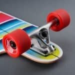 Kleine skateboard met kleurrijk ontwerp en rode wielen op een grijze achtergrond.