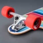 Kleine skatesboard met rode wielen, kleurrijke print en metalen trucks. Perfect voor buitenplezier en tricks.