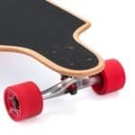 Korte houten skateboard met zwarte griplaag en rode wielen op een witte achtergrond.