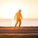 Skateboarder op de pier tijdens zonsondergang.