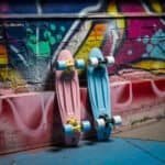 Pink en blauwe skateboards met wielen tegen een graffiti muur.