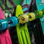 Kleurrijke skateboards met wielen hangen aan een graffiti muur.