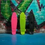 Pink skateboards, lime green skateboard en zwart skateboard op graffiti muur achtergrond.