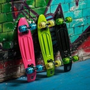 Pink skateboard met blauwe wielen tegen kleurrijke graf muur.