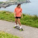 Skateboarden aan zee met vrouwelijke skater in sportkleding outdoor.