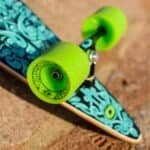 Kleurrijk skateboard met levendige groene wielen en een grafisch patroon op het deck. Perfect voor buitensport en skateboardplezier.