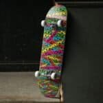 Skateboard met kleurrijk ontwerp en witte wielen, geschikt voor buitenplezier en skaten.