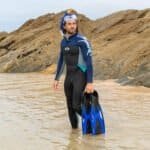 Vissen man in wetsuit met snorkel op het strand.