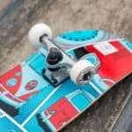 Kleurrijke skateboard met retro bus design en witte wielen, klaar voor buitenritten.