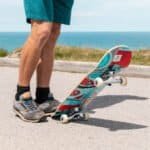 Skateboarder klaar om te skaten aan de kust met een kleurrijke skateboard.