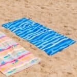 Summer beach towel with blue and pink stripes and seals, ideal for outdoor fun at the beach.