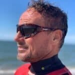 Lifestyle foto van man met watersportbril op het strand, genietend van de buitenlucht.