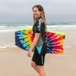 Koppel van surfkleding en wetsuit voor dames op het strand, klaar voor surfen.