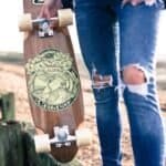 Skateboard met vintage ontwerp en houten deck, close-up van persoon in ripped jeans outdoors.