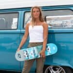 Comfortabele skateboard en jonge vrouw bij vintage camper voor buitenplezier.