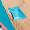 Blue windbreaker on sandy beach next to colorful wall, outdoor summer gear.