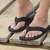 Detail van de comfortabele textiele teenband van de Log slipper aan voet op het strand