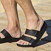 Man draagt zwarte Cool Shoe Corp Chill sandalen terwijl hij bij het strand ontspant