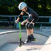 Kleine jongen op een scooter met beschermkleding in het skatepark.