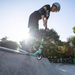 Scooter rider bij skatepark, outdoor skateboarding en scootering plezier, jonge skater op ramps.